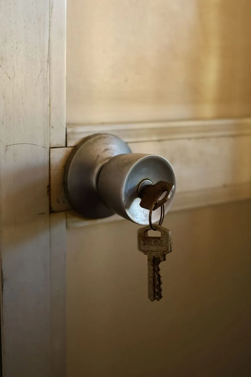 Llavín de pomo metálico con la llave puesta en una puerta de madera